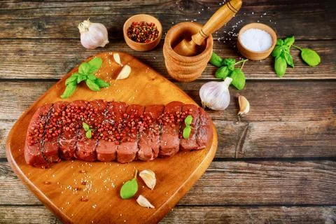 Piece of uncooked raw beef with spices on wooden board. Stock Photos