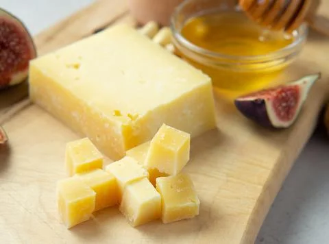 Pieces of aged cheese, nuts, figs and honey on a cutting board, Stock Photos