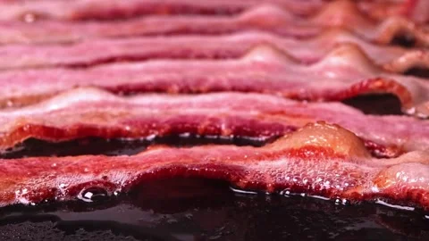 Pieces of bacon meat are fried in sizzling oil on hot skillet. 스톡 동영상 334643218