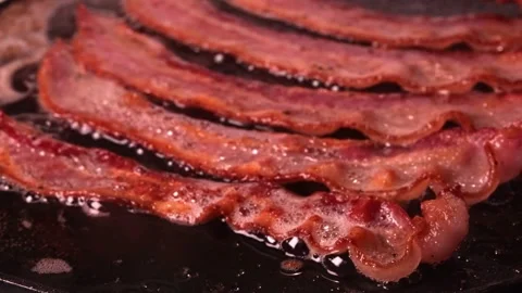 Pieces of bacon meat are fried in sizzling oil on hot skillet. 스톡 동영상 334643224