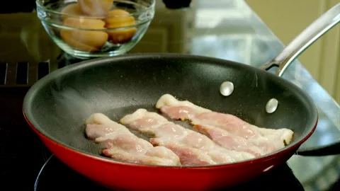 Pieces of bacon slices being flipped in a frying pan, close up shot. 스톡 동영상 334642338