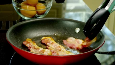 Pieces of bacon slices being flipped in a frying pan, close up shot. 스톡 동영상 334642352