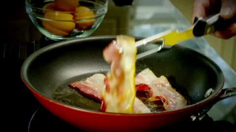 Pieces of bacon slices being flipped in a frying pan, close up shot. 스톡 동영상 334642359