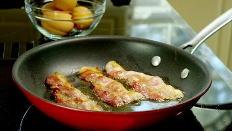 Pieces of bacon slices being flipped in a frying pan, close up shot. 스톡 동영상 334642461