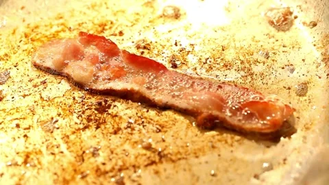 Pieces of bacon strips in a frying pan are fried in bubbles food of oil. 스톡 동영상 334642415