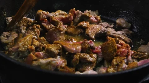 Pieces of beef are fried in a frying pan with oil and spices and turned ove.. Stock Footage 264520861
