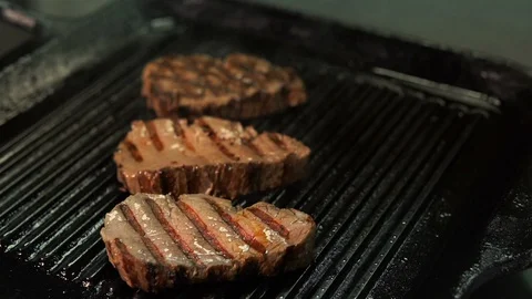 Pieces of beef are fried in a grill pan. Close-up of chef flips pieces of meat Stock Footage 113219959