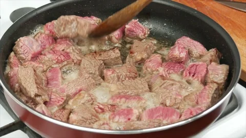 Pieces of beef meat fried in a pan, close-up, wooden spoon - healthy diet foo Stock Footage 133715008