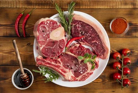 Pieces of beef of various kinds on a white plate. Pepper, cherry tomatoes, ro Stock Photos