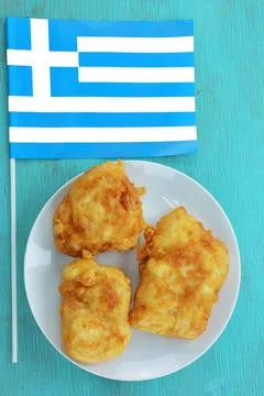Pieces of bread crumbed cod fish and Greek flag Stock Photos