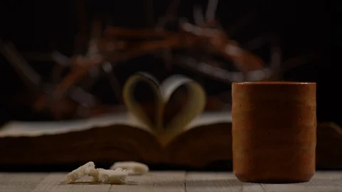 Pieces of Bread Dropping beside Cup with Bible and Thorn Crown in background Stock Footage 128595053