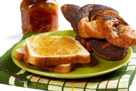 Pieces of bread with jam and rolls on a kitchen table Stock Photos