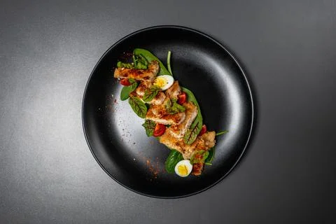 Pieces of brisket fried in batter with cherry tomatoes, leaves and egg. Stock Photos