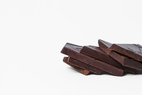 Pieces of broken dark chocolate on a light background. Stock Photos