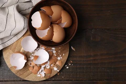 Pieces of broken eggshells on wooden table, top view. Space for text Foto stock