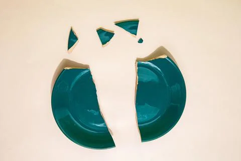 Pieces of broken plate on table in studio Stock Photos