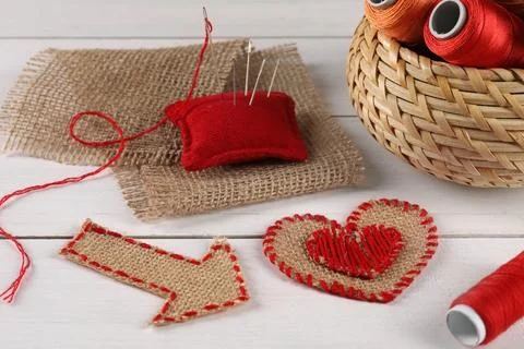 Pieces of burlap fabric, spools of threads, pincushion and needles on white.. Stockfoto's