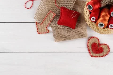 Pieces of burlap fabric, spools of threads, pincushion and needles on white.. Stockfoto's