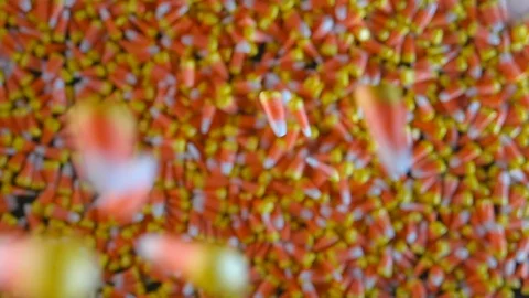 Pieces of candy corn are seen slowly dropping into a large pile of candy Stock Footage 116573178