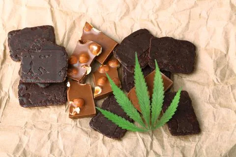 Pieces of chocolate with cannabis CBD nuts with dry green hemp leaf. Hemp bis Stock Photos