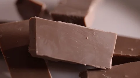 Pieces of chocolate rotating on a plain background Stock Footage 87857518