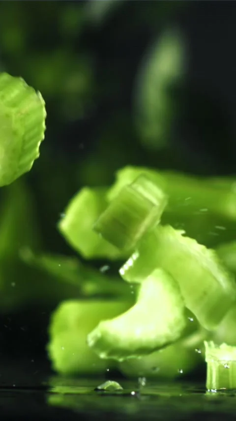 Pieces of chopped celery fall on the table. Filmed on a high-speed camera at Stock Footage 335304215