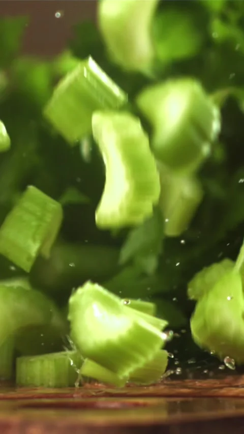 Pieces of chopped celery fall on the table. Filmed on a high-speed camera at Stock Footage 335314997