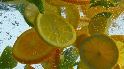 Pieces citrus fruit dropped with mint in water closeup. Sliced orange lemon lime Vidéo 218390748