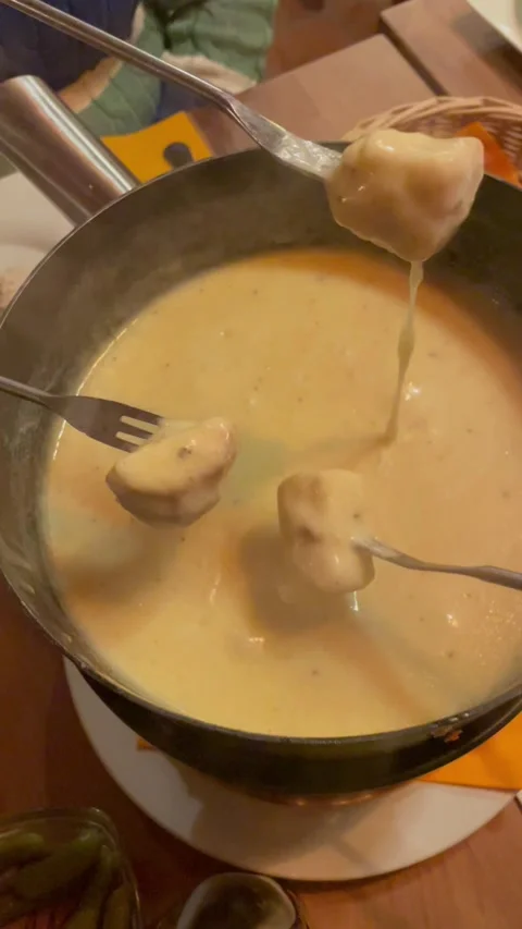 Pieces of crusty bread dipped into a steaming pot of melted cheese fondue Stock Footage 329888501