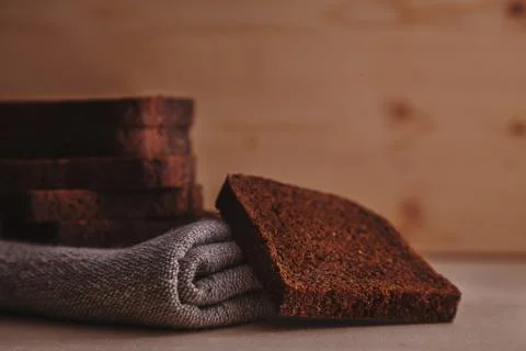 Pieces of dark rye bread and linen towel composed on a light wooden table Foto stock