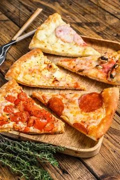 Pieces of different pizza various types. Wooden background. Top view Stock Photos