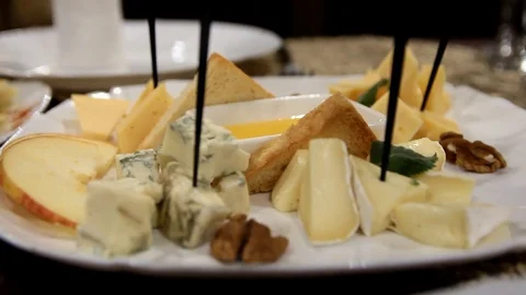 Pieces of different varieties of cheese and nuts lie on a white plate Stock Footage 123624007