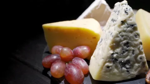 Pieces of different varieties of cheese on a black wooden table close-up. An Stock Footage 156813347