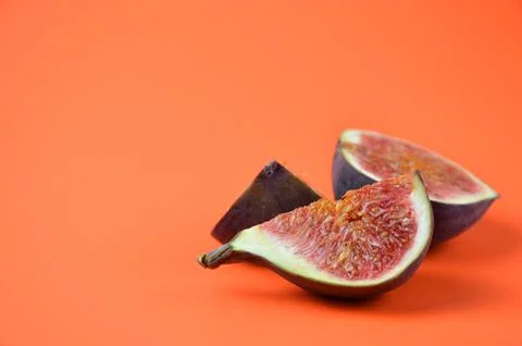Pieces of figs on an orange background. Stock Photos