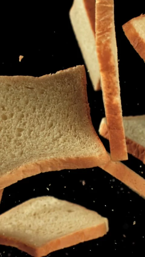 Pieces of fresh bread fly up against a black background. Filmed on a high-speed Stock Footage 335371593