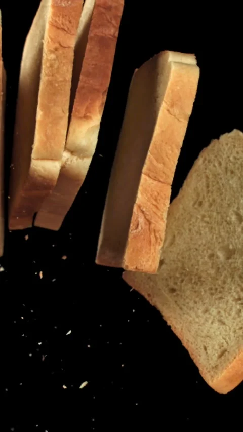 Pieces of fresh bread fly up against a black background. Filmed on a high-speed Stock Footage 335374753