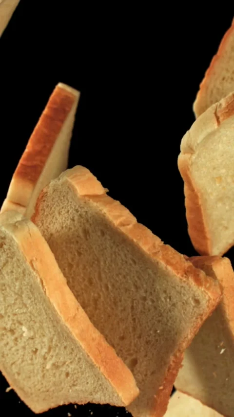 Pieces of fresh bread fly up against a black background. Filmed on a high-speed Stock Footage 335375701