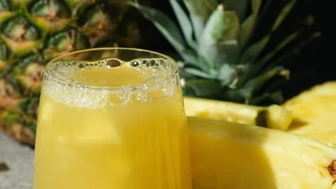 Pieces of fresh pineapple fall into pineapple juice, juice splash slow motion. Stock Footage 296372223