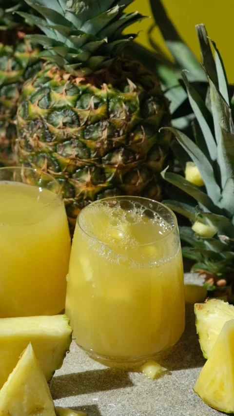 Pieces of fresh pineapple fall into pineapple juice, juice splash, vertical slow Stock Footage 296682055