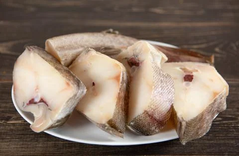 Pieces of fresh raw fish cod on a wooden background Stock Photos