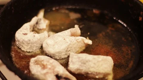 Pieces of freshwater fish frying in a cast-iron skillet Stock Footage