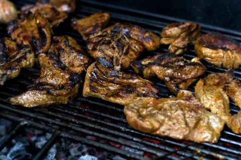 Pieces of fried meat on a grate, with smoke and fire. Stock Photos
