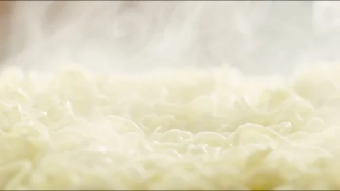 Pieces of fried sausages fall on hot noodles with steam. slow motion Video stock 86572030