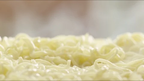 Pieces of fried sausages fall on hot noodles with steam. slow motion Video stock 86572501
