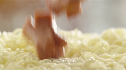 Pieces of fried sausages fall on hot noodles with steam. slow motion Video stock 86572677