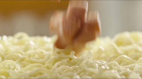 Pieces of fried sausages fall on hot noodles with steam. slow motion Video stock 86573575