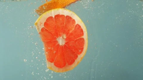 Pieces of grapefruit gently float in the water, forming tiny air bubbles. Stock Footage 265252952