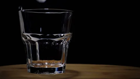 Pieces of ice falling in slow motion into an empty glass Stock Footage 120981746