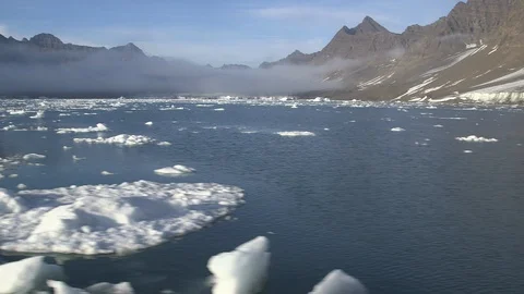 Pieces of ice floe in the Arctic Ocean with mountains in the background Video stock 103503151