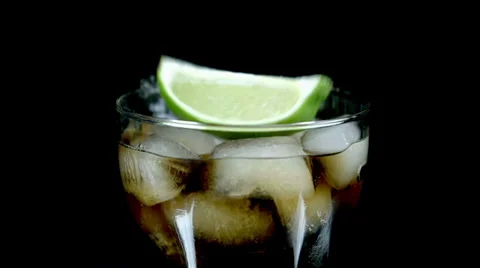 Pieces of lime fall into coke with ice cubes in slow motion Stock Footage 33008165